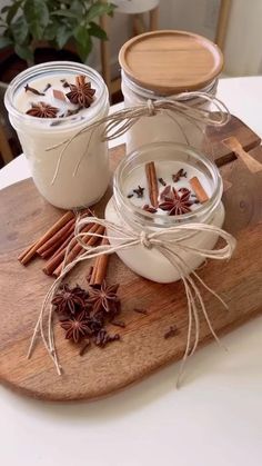 some cinnamon sticks and spices are on a cutting board next to two glass jars with cinnamons in them