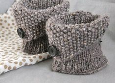 two knitted boots sitting on top of a white and brown polka dot cloth next to a pillow