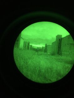 the view through a circular lens at an old building in a field with tall grass