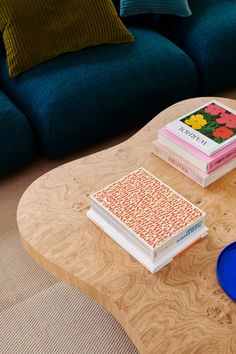 a coffee table with books on it in front of a blue couch and green cushions