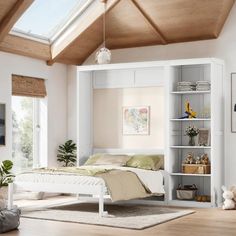 a white bed sitting under a window next to a book shelf filled with books on top of a wooden floor