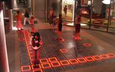 a group of people standing around in a room with red and yellow squares on the floor