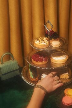 a person reaching for pastries on three tiered trays