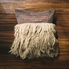 a decorative pillow with long, shaggy hair on it's back rests against a wooden wall