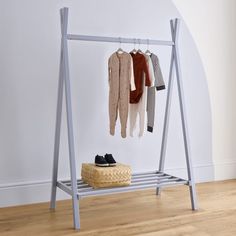 an ironing board with clothes hanging from it's hooks and two pairs of shoes