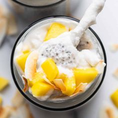 two glasses filled with fruit and yogurt on top of a white tablecloth