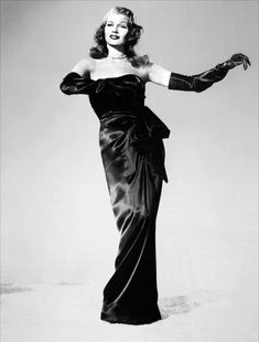 a black and white photo of a woman in a long dress with her arms outstretched