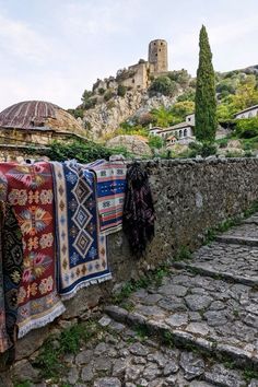 some blankets are hanging on a stone wall