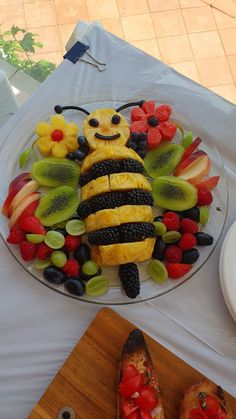 a plate that has some fruit on it and a bee made out of sliced fruits