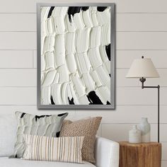 a living room with a white couch and black and white painting on the wall above it