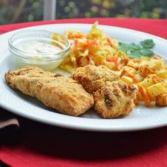 a white plate topped with fried food next to a bowl of ranch dressing on top of a red table cloth