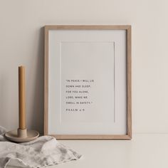 a white framed print with a candle on a table next to it and a napkin