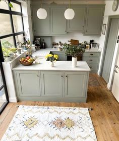 a kitchen with gray cabinets and white counter tops, an area rug on the floor