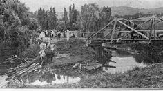 an old black and white photo of people crossing a bridge