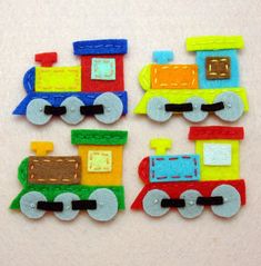 there are three different colored train magnets on the table together, one is red, one is yellow and one is green