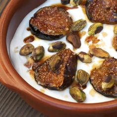 an orange bowl filled with nuts and yogurt on top of a wooden table