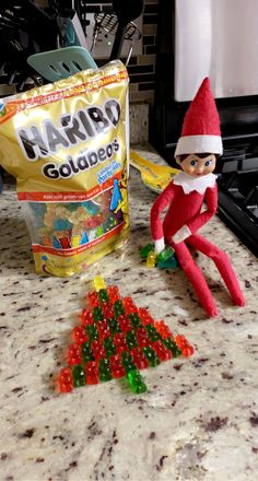 an elf is sitting on the counter next to some gummy candies and a bag of harro goldfingers