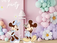 two mickey mouse cut outs sitting in front of balloons