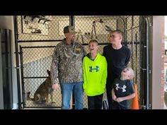 a man and two boys are standing in front of a gate with dogs on the other side