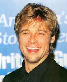 a close up of a person wearing a black shirt and tie smiling at the camera