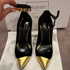 Pre Owned Authentic Balmain Paris Black And Gold Velvet Pumps With Gold Metal Ankle Closure Size 37 Made In Italy Comes With Original Box And Dust Bag Very Minor Scuff Front Of Right Side Adjustable Ankle Closure Party Court Shoes With Ankle Strap And Contrasting Heel, Luxury Ankle Strap Court Shoes For Office, Court Shoes With Contrasting Heel Counter For Party, Luxury Court Shoes With Padded Heel For Evening, Luxury Gold Heels With Contrasting Heel Counter, Designer Heels With Contrasting Heel Counter And Pointed Toe, Designer Heels With Contrasting Heel And Pointed Toe, Designer Pointed Toe Heels For Fashion Events, Luxury Evening Court Shoes With Heel Strap