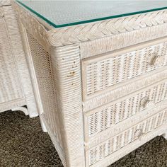 a white wicker dresser with glass top on carpeted flooring in living room