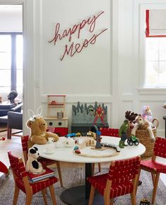 there are many stuffed animals sitting at the table in this room with red chairs and a happy new year sign on the wall