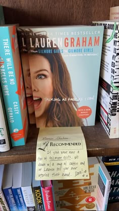 a book shelf with several books on it and a note attached to the front cover