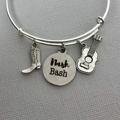 It's a Nash Bash, Y'all! This will be the perfect accessory when going out in music city with all of your friends. Nash Bash Charm Bangle Bracelet * Perfect gift for your bachelorette party or celebrating a party in Nashville, Tn * Adjustable silver plated bracelet (61mm) Features three lovely charms * Stainless steel Nash Bash charm (19mm x 22mm) * Boot and guitar is made of zinc alloy metal -- lead and nickel free! * Delivered in a cute ready-to-give kraft gift box It's easy to add other cute Adjustable Themed Jewelry For Parties, Silver Novelty Bracelets For Party, Adjustable Bracelets For Party Festival, Adjustable Bracelets For Party And Festival, Novelty Custom Name Jewelry For Birthday, Custom Name Novelty Jewelry For Birthday, Custom Name Jewelry For Birthday, Custom Name Novelty Jewelry For Birthdays, Novelty Custom Name Jewelry For Birthdays