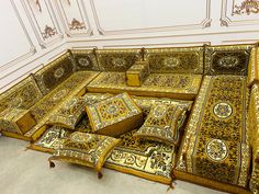 an elaborately decorated couch in the middle of a room with white and gold walls