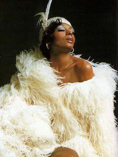 a woman in a white dress and feather shawl