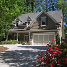 a house that is in the middle of a driveway with flowers growing on the side