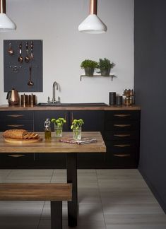 a kitchen with a table and two lights hanging over the counter top next to a potted plant