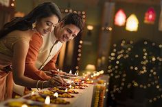 a man and woman standing in front of a table with candles on it while looking at something