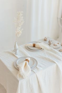 the table is set with white linens and place settings for two people to eat