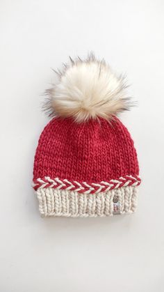 a red and white knitted hat with a pom - pom on top