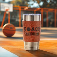 an orange and silver tumbler cup sitting on top of a basketball court