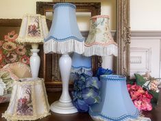 three blue lamps are sitting on a table next to a mirror and flowers in vases