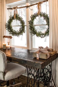 two wreaths on the window sill in front of a table with a sewing machine