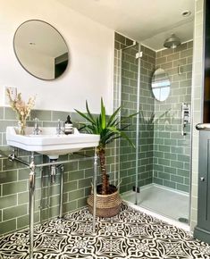 a green tiled bathroom with a sink, mirror and plant in the corner on the floor