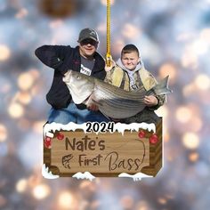 a man and boy are holding a fish on a sign that says nafes and first bass