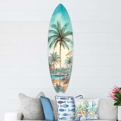 a surfboard is hanging on the wall next to a couch with pillows and flowers