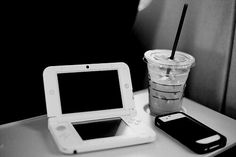 a table with a cup, cell phone and tablet on it next to a drink