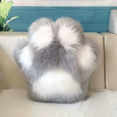 a grey and white fur pillow sitting on top of a couch