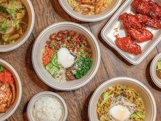 many different bowls of food on a wooden table