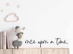 a stuffed animal sitting on top of a wooden shelf in front of a white wall