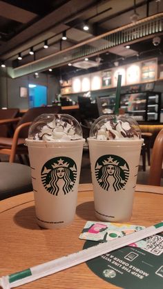 two starbucks drinks sitting on top of a wooden table