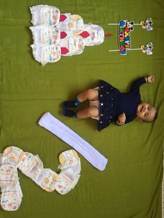 a baby laying on top of a green blanket next to diapers