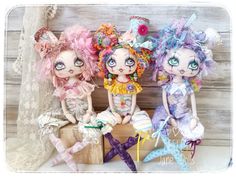 three dolls sitting on top of a wooden box