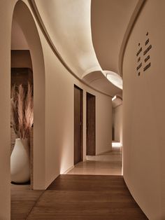 the hallway is lined with white vases and wood flooring, along with an arched wall